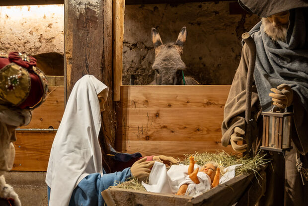 Die Krippe im Heimatmuseum Sixenhof Das Bild zeigt eine Weihnachtskrippe im Heimatmuseum Sixenhof in Achenkirch mit Figuren von Maria, Josef und einem Neugeborenen im Stroh. Im Hintergrund ist ein Esel zu sehen.