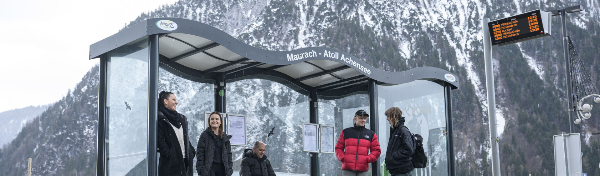 Eine Gruppe von Menschen wartet im Winter auf den Bus im Atoll Achensee.