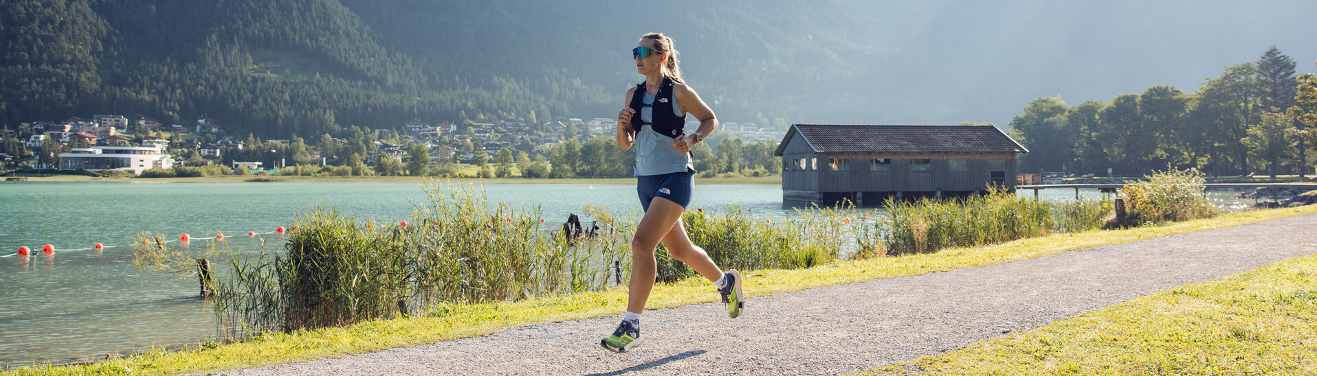 Running along the Seespitz A woman jogs along the Seespitz in fine weather, while the boathouse can be seen in the background.