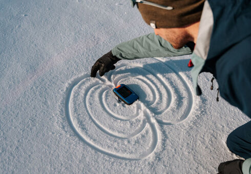 Notfall Lawine Ein Skitourengeher hält sein lebensrettendes Lawinenverschüttetensuchgerät (LVS) in der Hand.