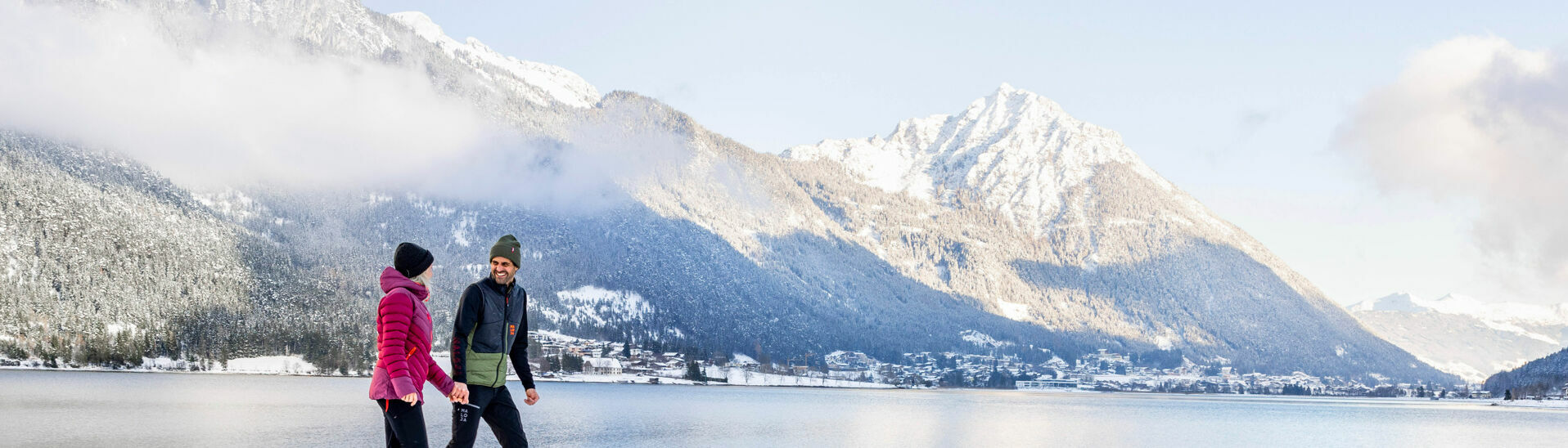 Winter walk in Pertisau am Achensee A couple enjoying a winter walk in the snowy landscape of Lake Achensee, backdropped by Maurach and the Ebner Joch.
