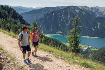 Ein Pärchen wandert entlang eines Wanderweges im Rofangebirge und genießt die tolle Wiese rundherum.