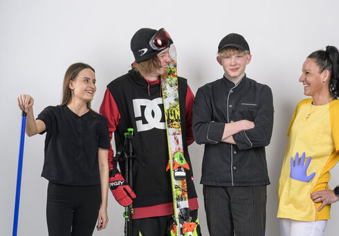 AMS: Services for job seekers This photo captures a hotel housekeeper, a skier, an apprentice chef and a care worker holding the Achensee DahoamCard in front of a white screen.