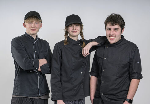Lehre am Achensee Zwei auszubildende Köche und eine Konditorin posieren vor einer weißen Wand.